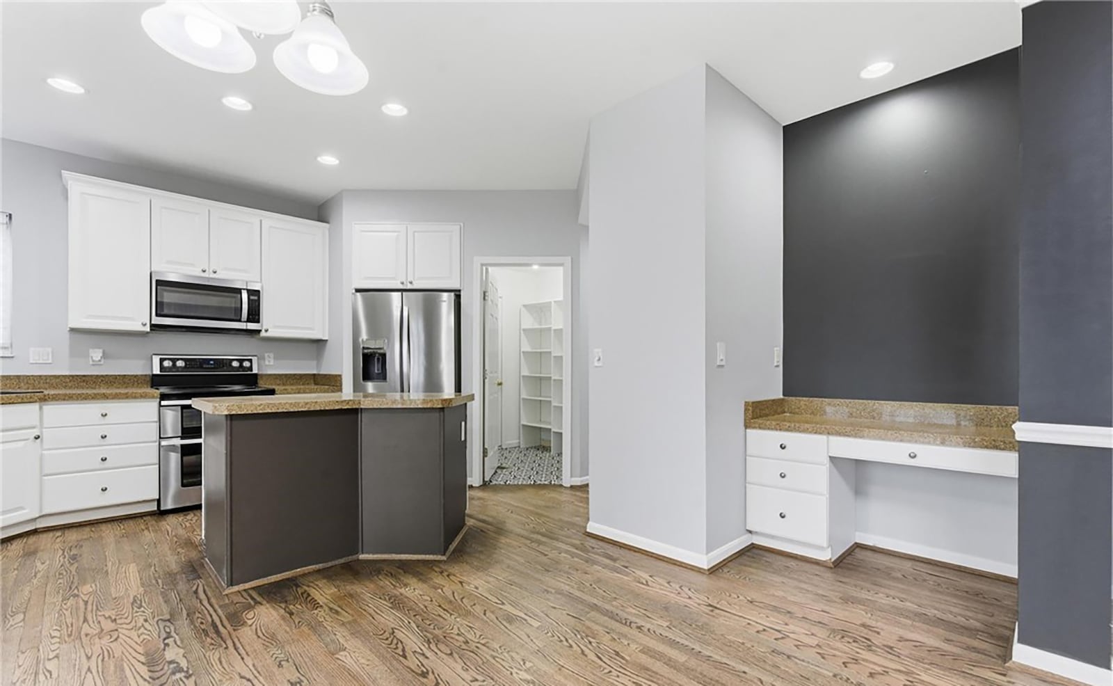 The kitchen has hardwood floors, white wood cabinets and granite countertops. There is an island with bar seating and a breakfast nook with access to the back patio. CONTRIBUTED