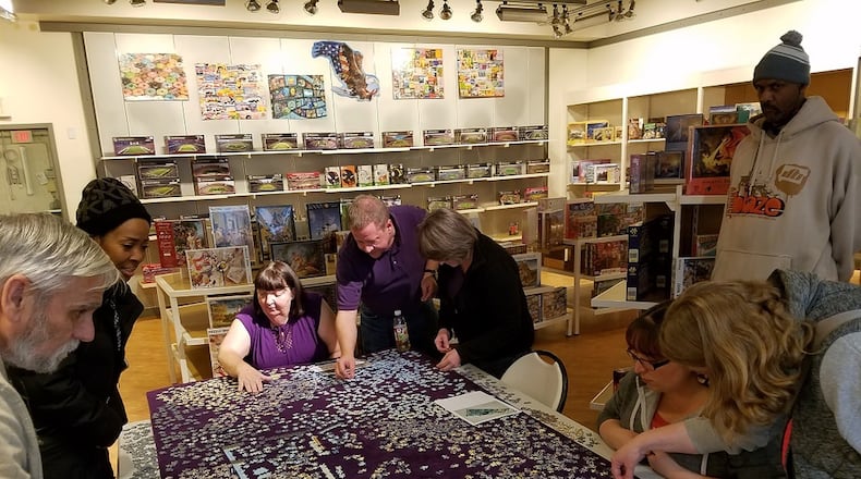 Virgil Chenoweth (from left), Jackie Givens, Cindy Chenoweth, Steve Nordmeyer, Lisa Nordmeyer, Diane Chenoweth, Kim Lever and David Givens tackle a 32,000-piece puzzle at Puzzles Plus at The Greene in Beavercreek. CONTRIBUTED