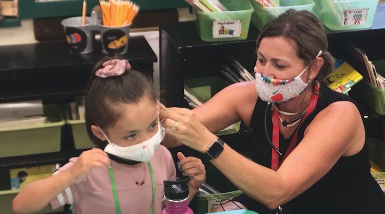Heywood Elementary School first-grade teacher Angela Laird (right) helps student Madalyn Lee adjust her face mask on Troy City Schools' first day of school in fall 2020.