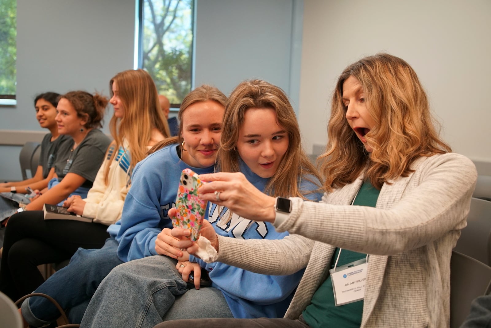 From right, coach Amy Miller, Larkin Wilson, Sadie Osenga, Thalia Vidalakis, Katherine Thomas and Ashley Maliakal from The Harpeth Hall School in Nashville, Tenn., take a selfie during a match at the National High School Ethics Bowl in Chapel Hill, N.C., on Sunday, April 13, 2025. (AP Photo/Allen G. Breed)