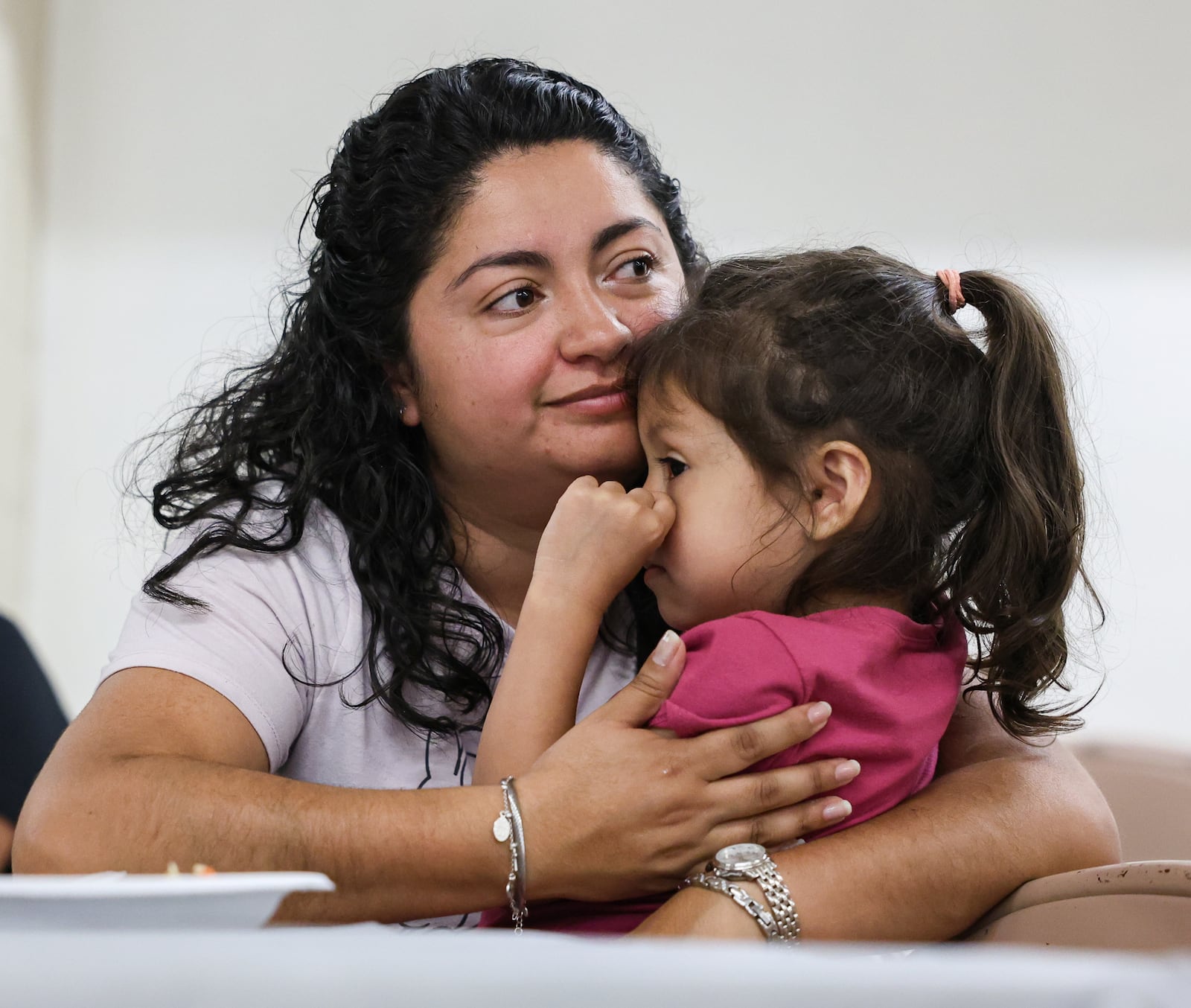 Diana Castillo hugs her daughter Violet Mendez during a lunch hosted by Cross Over Community Development on Tuesday at Christ Evangelical Lutheran Church in Dayton. Castillo is one participant in a new program offered by the nonprofit that is designed to provide language skills to immigrants seeking employment in the medical field. BRYANT BILLING / STAFF