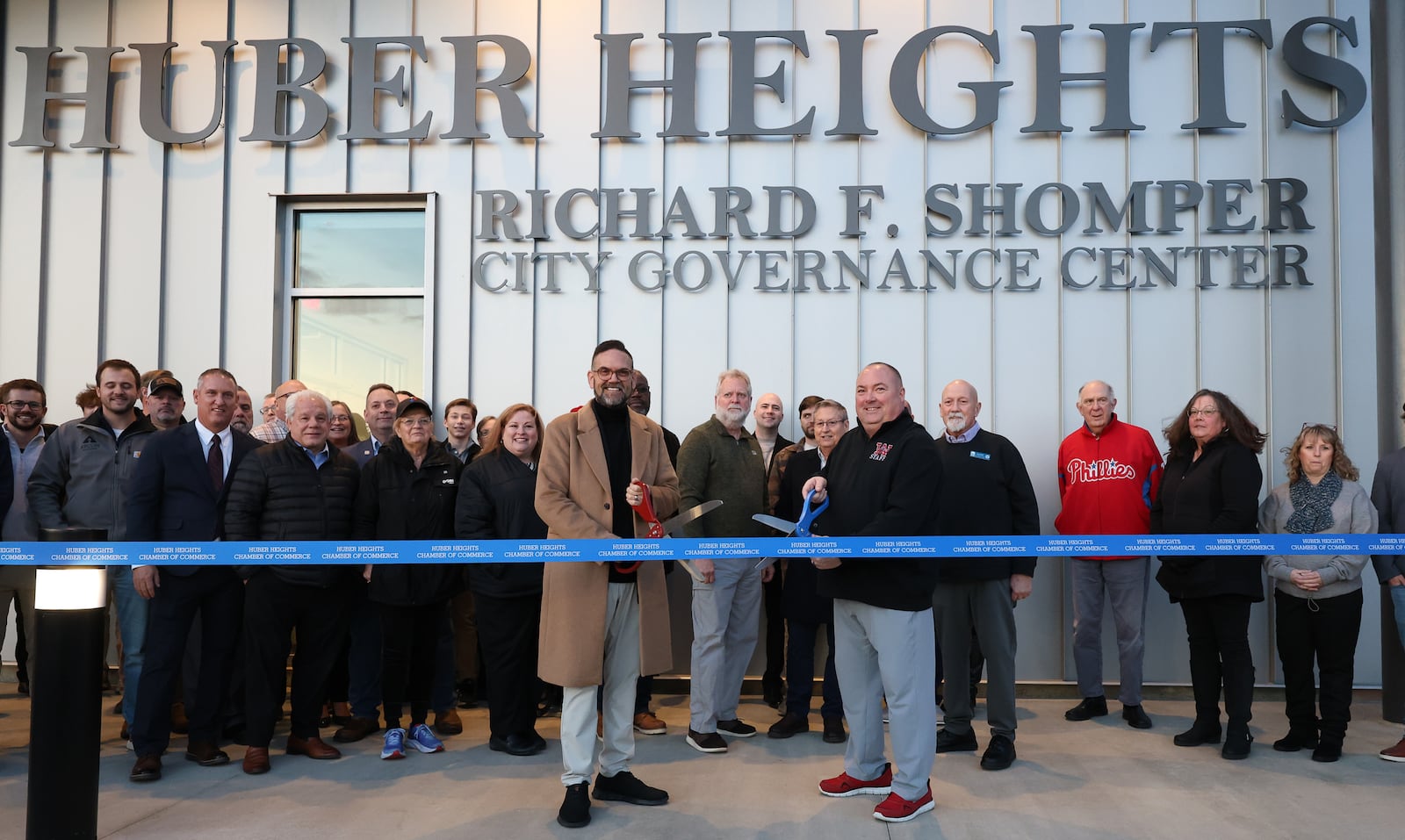 Huber Heights mayor Jeff Gore (center left) and Matt Shomper (center right) pose along with other Huber Heights officials and Shomper family members before a ribbon cutting on Tuesday, Dec. 9 at the new Richard F. Shomper City Governance Center on Brandt Pike. The new facility is named after Huber Heights’ inaugural mayor. BRYANT BILLING/STAFF