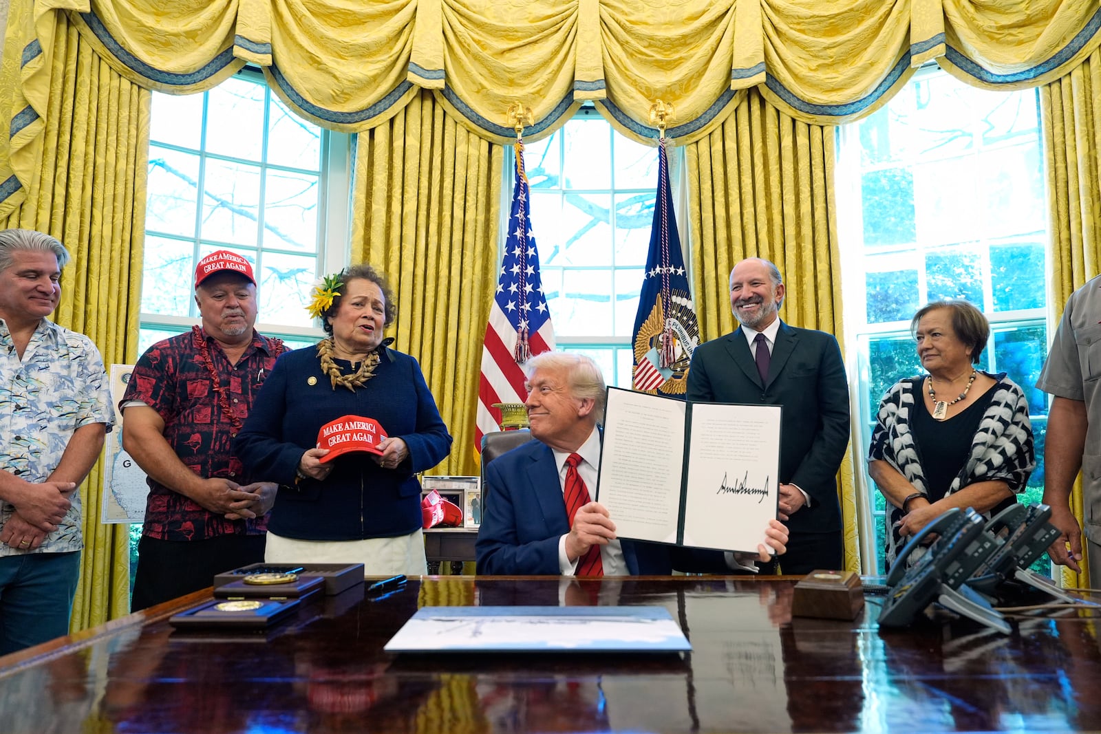 President Donald Trump holds a signed executive order regarding commercial fishing in the Pacific as he speaks in the Oval Office of the White House, Thursday, April 17, 2025, in Washington. (AP Photo/Alex Brandon)