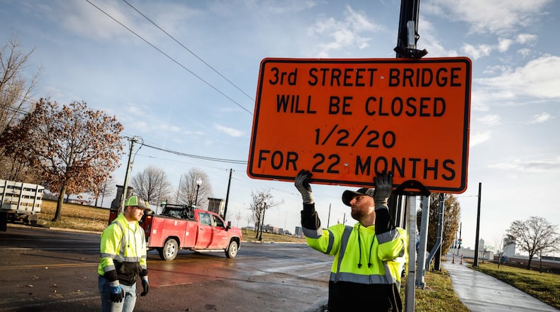 Kevin Kirk, left and Wes Minton remove road closed sign off the westside of the newly rebuilt Third Street bridge Thursday Dec. 2, 2021. JIM NOELKER/STAFF