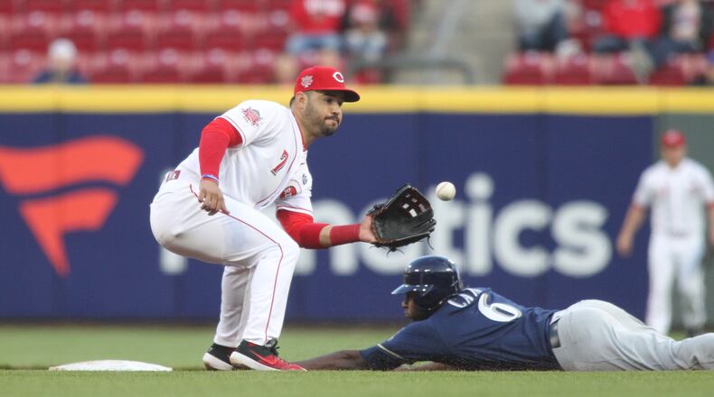 Reds third baseman Eugeno Suarez waits for a throw from catcher Tucker Barnhart as the Brewersâ Lorenzo Cain steals second on Tuesday, April 2, 2019, at Great American Ball Park in Cincinnati.