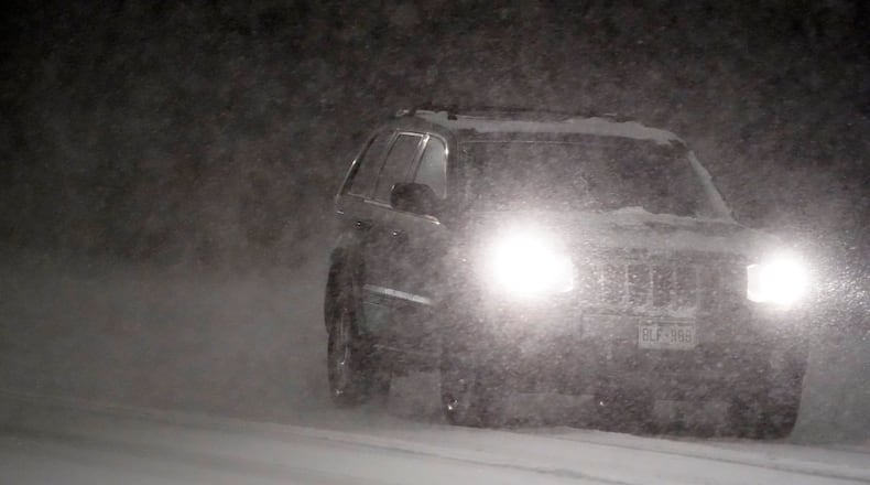 A motorist guides an SUV along a street as a heavy snowfall swept over the region Wednesday night, Feb. 24, 2021, in Denver. (AP Photo/David Zalubowski)