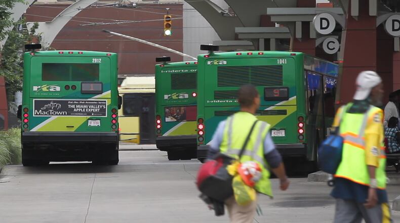 Workers arrive at the Wright Stop Plaza in downtown Dayton to catch a bus. TY GREENLEES / STAFF