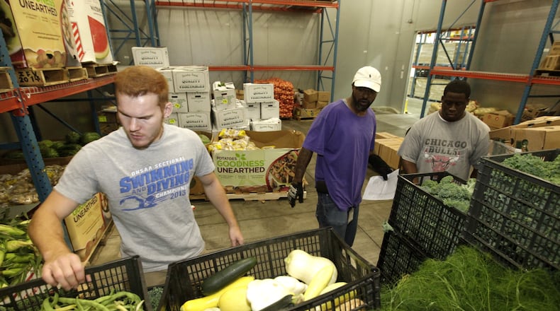 Cameron Rohrer, an employee of The Foodbank, Clark Brunson Jr., a volunteer and JaMichael Stallings, a Foodbank employee, (left to right) fill food orders to be picked up and distributed by area agencies in Dayton. Despite a decrease in the national poverty rate from 2015 to 2016, more local residents are turning to The Foodbank for assistance. LISA POWELL / STAFF PHOTO