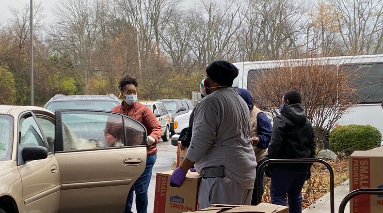 Annette Thomas, left, opens a car door so Robert Strozier, right, can place a box of food in the car at St. Luke Missionary Baptist Church in Dayton on Saturday.