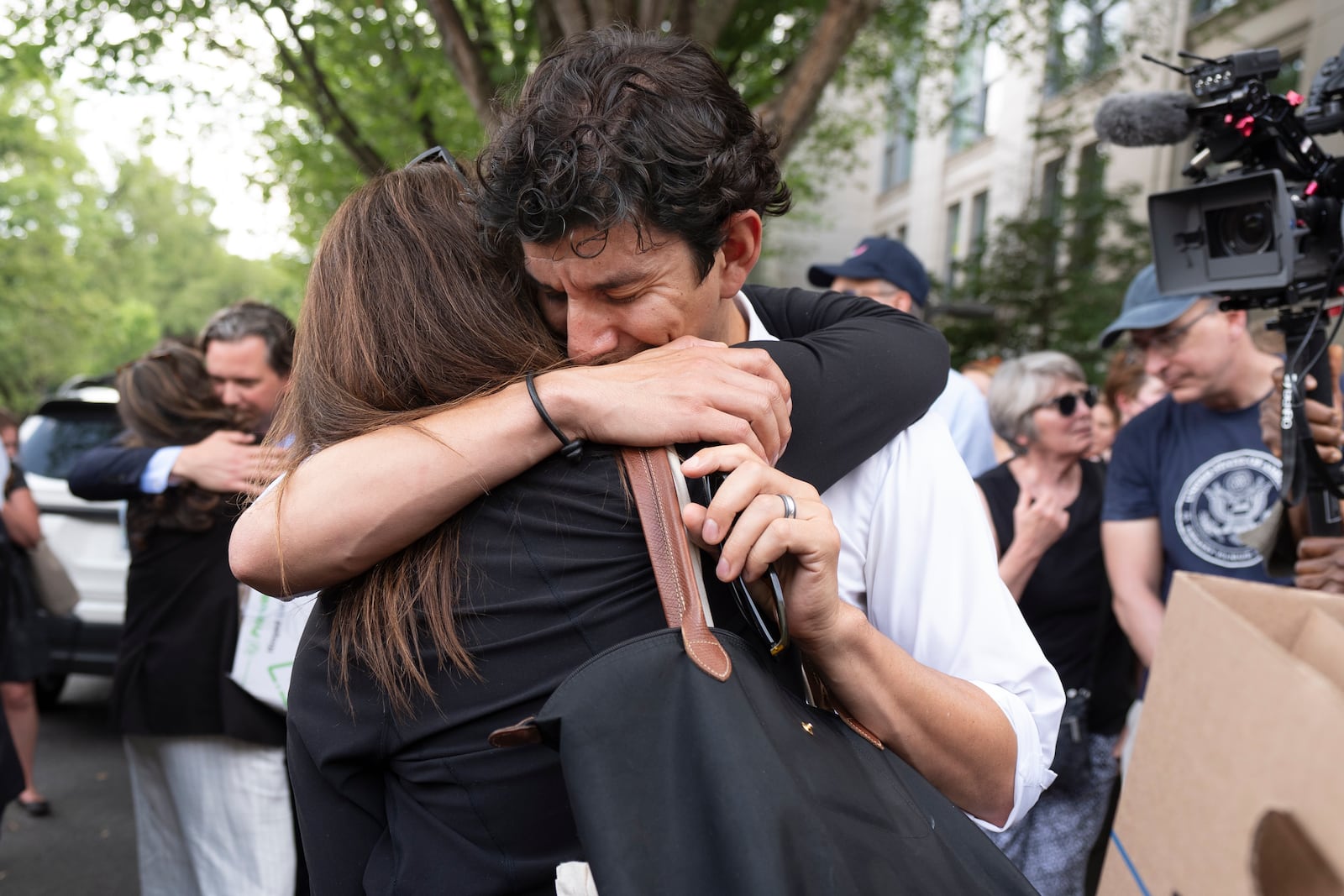 FILE - A fired State Department employee, left, is greeted outside of the Harry S. Truman Building, the headquarters of the State Department, in Washington, July 11, 2025. (AP Photo/Manuel Balce Ceneta, File)