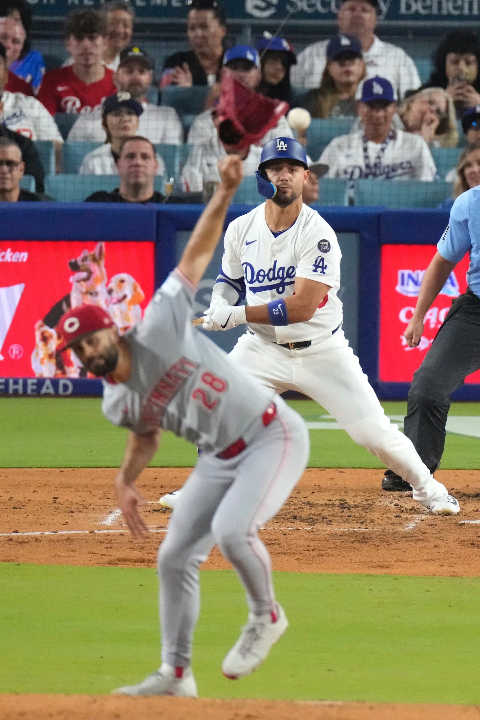 Cincinnati Reds starting pitcher Nick Martinez, left, has his glove knocked off by a single hit by Los Angeles Dodgers' Michael Conforto during the fourth inning of a baseball game Tuesday, Aug. 26, 2025, in Los Angeles. (AP Photo/Mark J. Terrill)