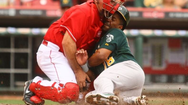 Reds catcher Corky Miller tags out the A's Alberto Callaspo as they collide at home after a throw from Jay Bruce in the fourth inning on Wednesday, Aug. 7, 2013, at Great American Ball Park in Cincinnati. David Jablonski/Staff