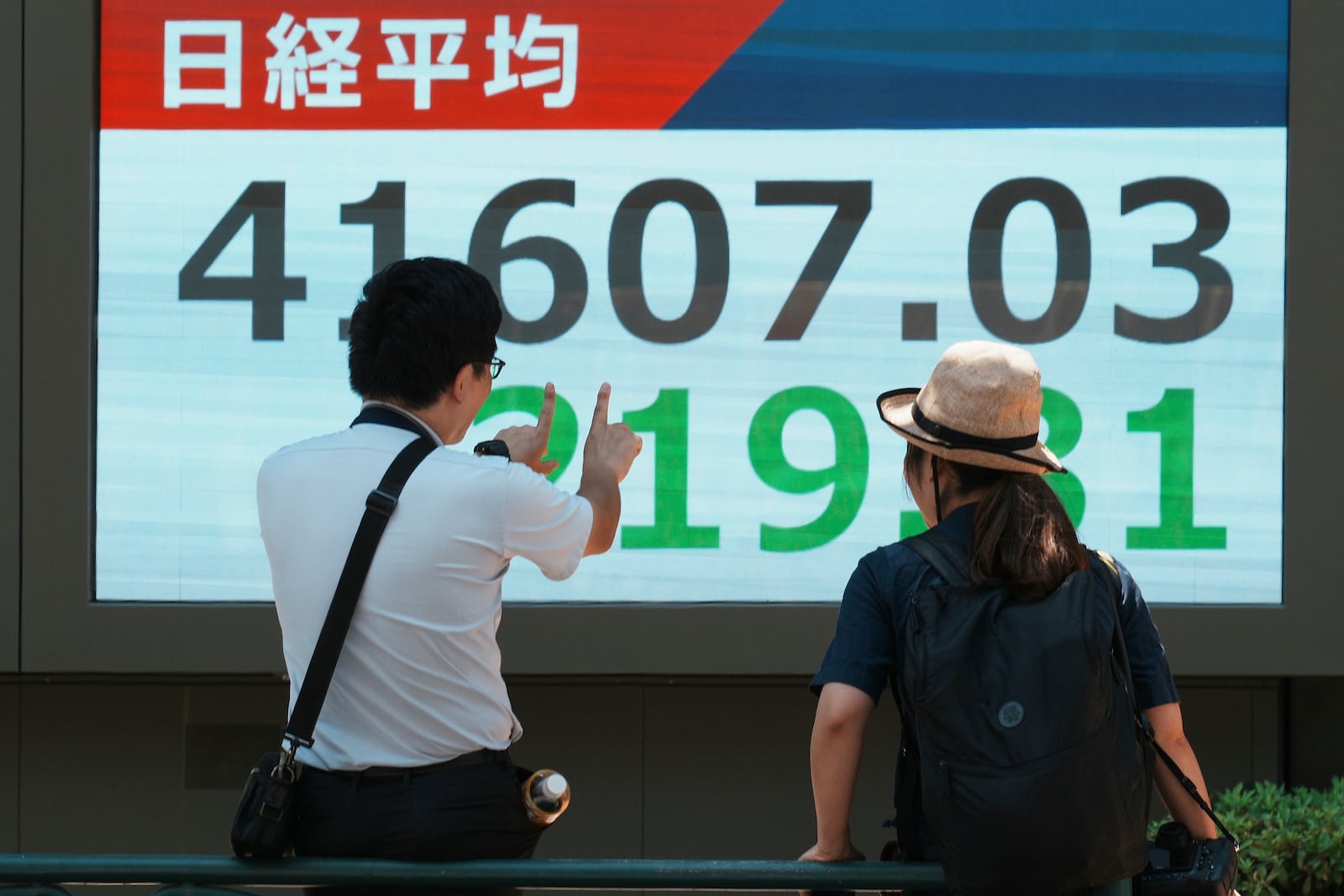 People speak in front of an electronic stock board showing Japan's Nikkei index at a securities firm Friday, July 25, 2025, in Tokyo. (AP Photo/Eugene Hoshiko)