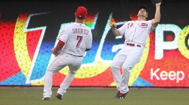 Reds right fielder Adam Duvall, right, makes a catch as shortstop Eugenio Suarez watches against the Cardinals on Wednesday, June 8, 2016, at Great American Ball Park in Cincinnati. David Jablonski/Staff