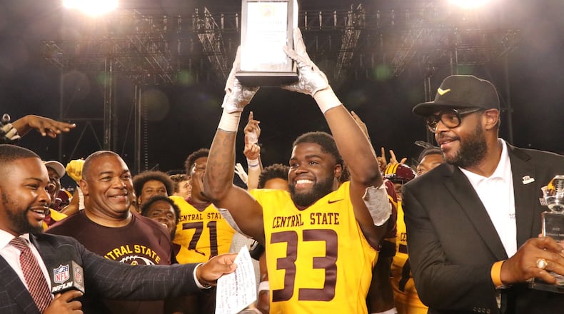 Central State's Jalil Lenore (33) and head coach Kevin Porter accept Black College Football Hall of Fame Classic trophy from Central State Hall of Famer Erik Williams on Sunday night in Canton. Nick Novy/Central State Athletics