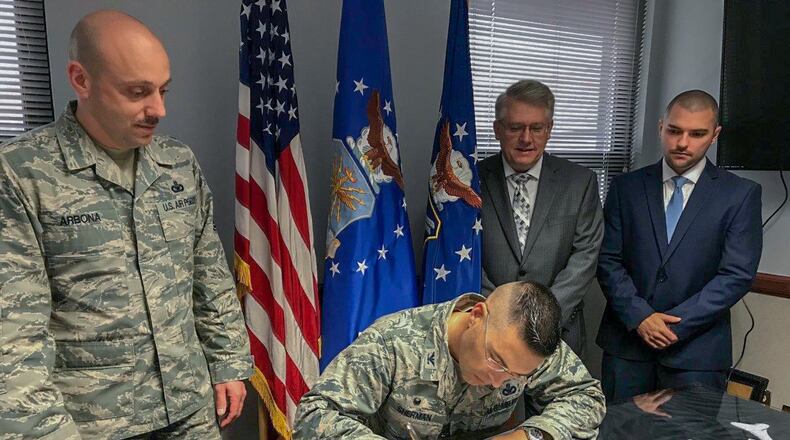 Right to left, 88th Civil Engineering Group Energy Manager Noah Fillian, Installation Planning chief Michael Tibbs, and Chief Master Sgt. Stephen Arbona, 88th Air Base Wing command chief, look on while Col. Thomas Sherman, 88th Air Base Wing and installation commander, signs an Energy Action Month proclamation to declare October 2018 as Wright-Patterson Air Force Base Energy Action Month. (U.S. Air Force photo/Stacey Geiger)