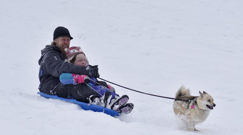 Jason Bender and Breanna Bender, 8, sled IN the snow with their dog, Lucy, Tuesday, February 9, 2021 at Harbin Park in Fairfield. NICK GRAHAM / STAFF