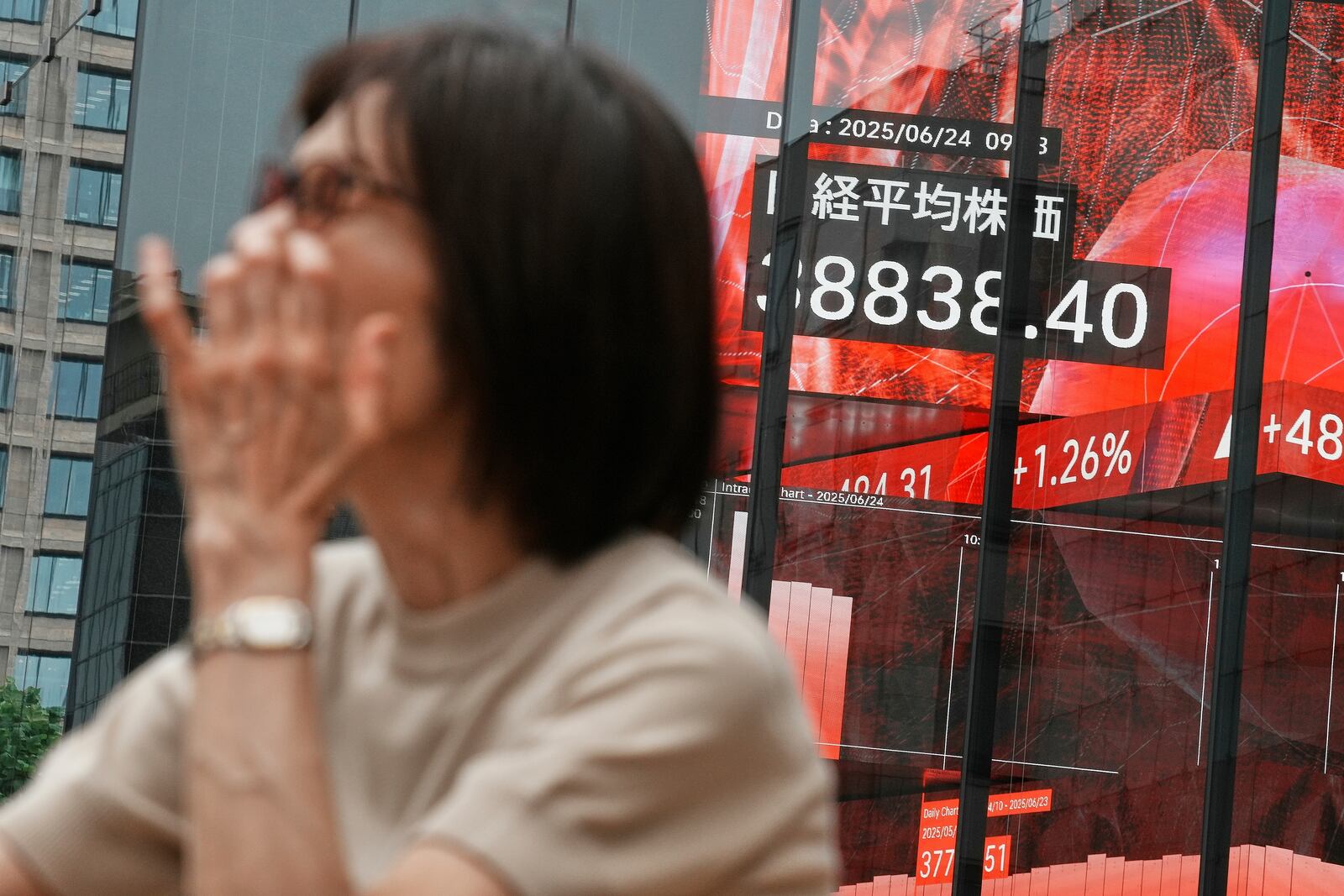 A person stands in front of an electronic stock board showing Japan's Nikkei index at a securities firm Tuesday, June 24, 2025, in Tokyo. (AP Photo/Eugene Hoshiko)