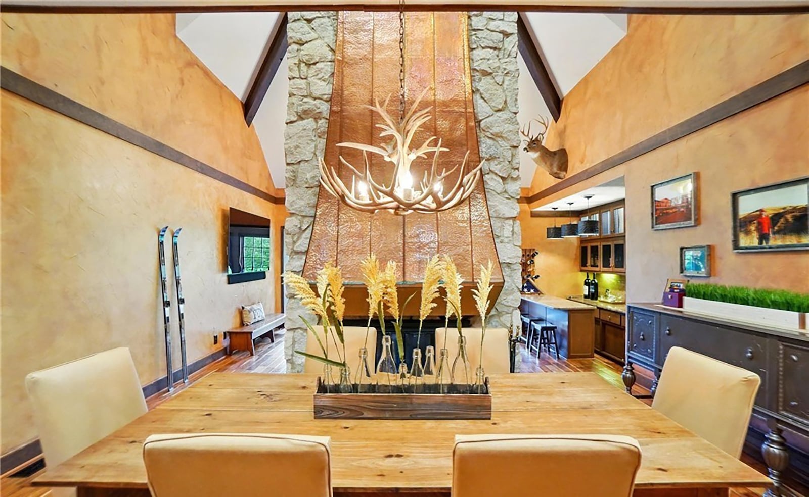 The open concept dining and family rooms has hardwood flooring throughout and a floor to ceiling two sided stone fireplace with custom copper hood.