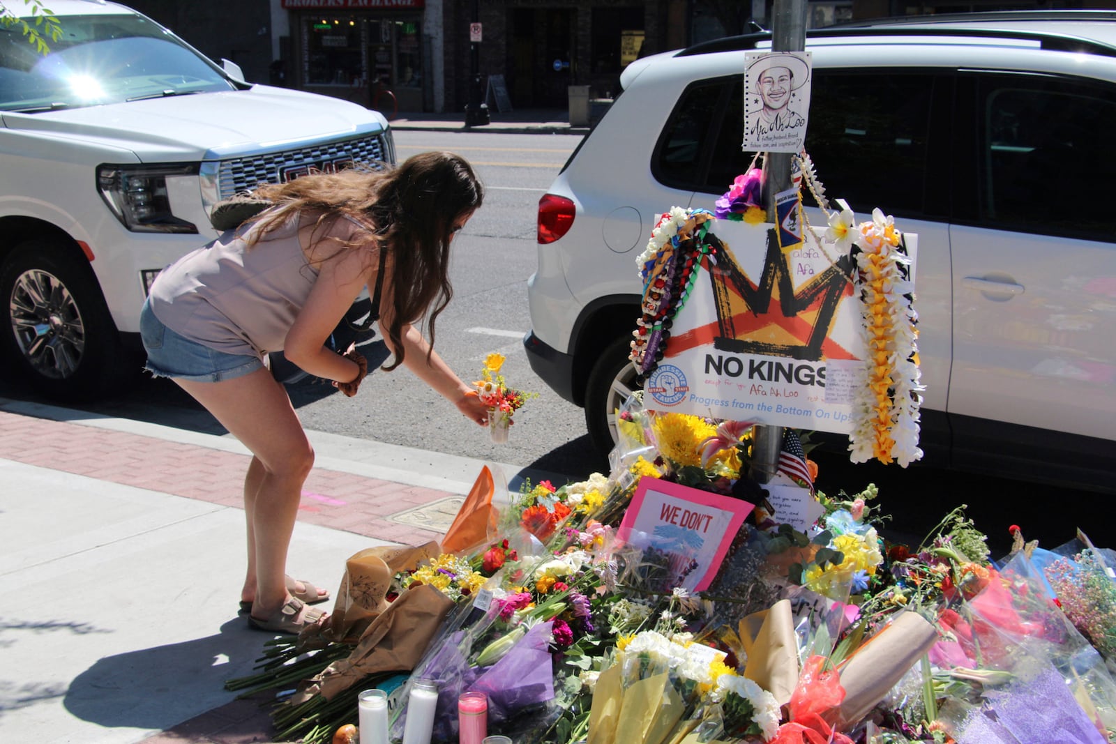 A woman lays flowers Tuesday, June 17, 2025, at a makeshift memorial for Arthur Folasa Ah Loo, known to friends and family as Afa, on the city block in Salt Lake City, Utah, where Ah Loo was fatally shot during a "No Kings" protest on Saturday, June 14. (AP Photo/Hannah Schoenbaum)