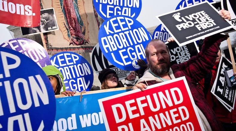 A pro-life activist stands in front of pro-choice activists with the National Organization For Women at a vigil outside the U.S. Supreme Court on January 23, 2012 in Washington, DC. The vigil was held to mark the anniversary of the Roe v. Wade Supreme Court decision that legalized abortion. (Photo by Brendan Hoffman/Getty Images)