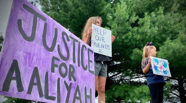 A protest over the handling of complaints in connection to Aaliyah Artis, a 12-year old girl who died in Xenia in June, took place on front of Greene County Children Services Tuesday.  Wearing a bow, Joezie Jobes, and Lily Redmond, hold signs at the protest. MARSHALL GORBY\STAFF