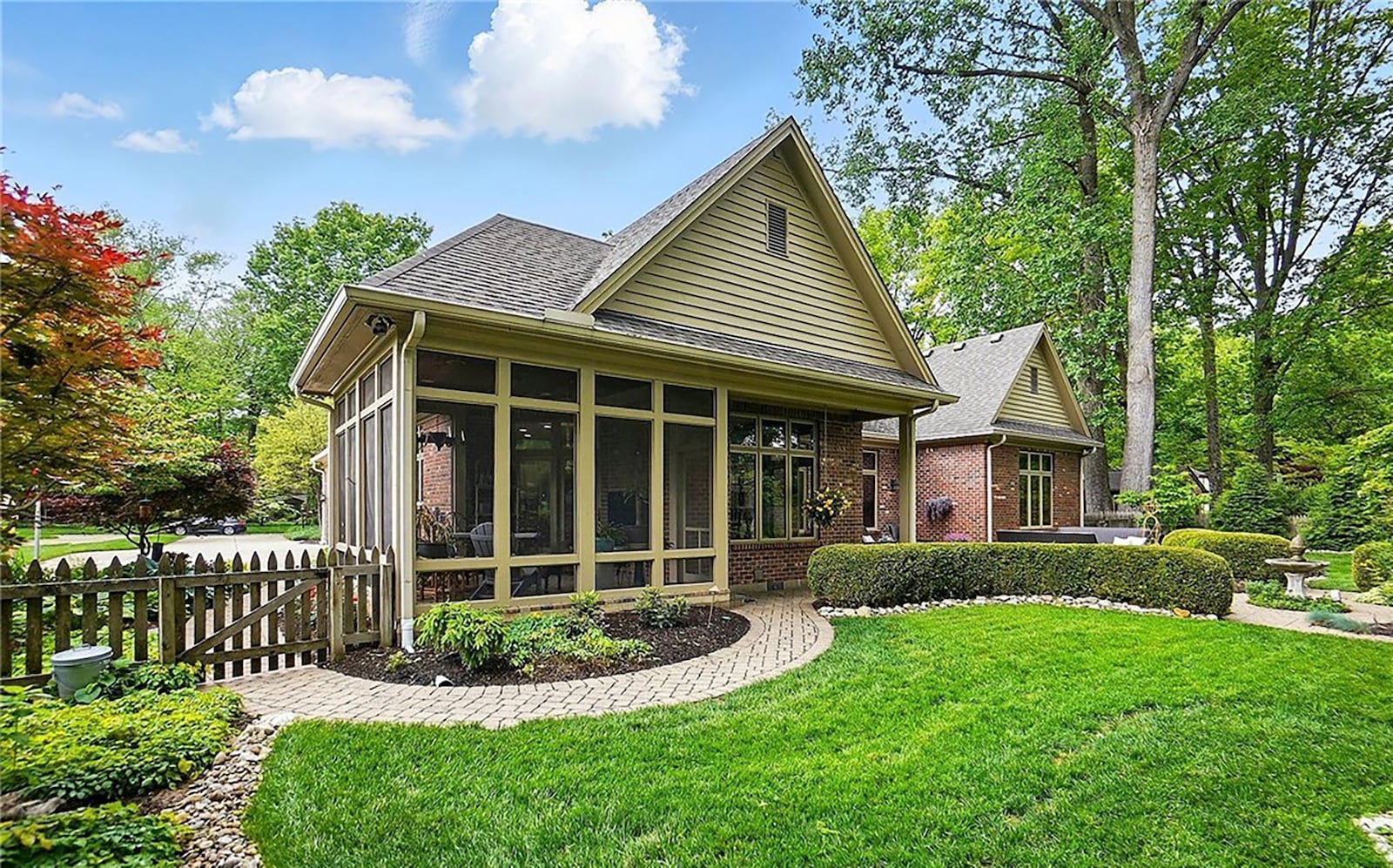 The rear of the home features the screen in porch and a paver patio with walkways connecting to areas in the fenced backyard.