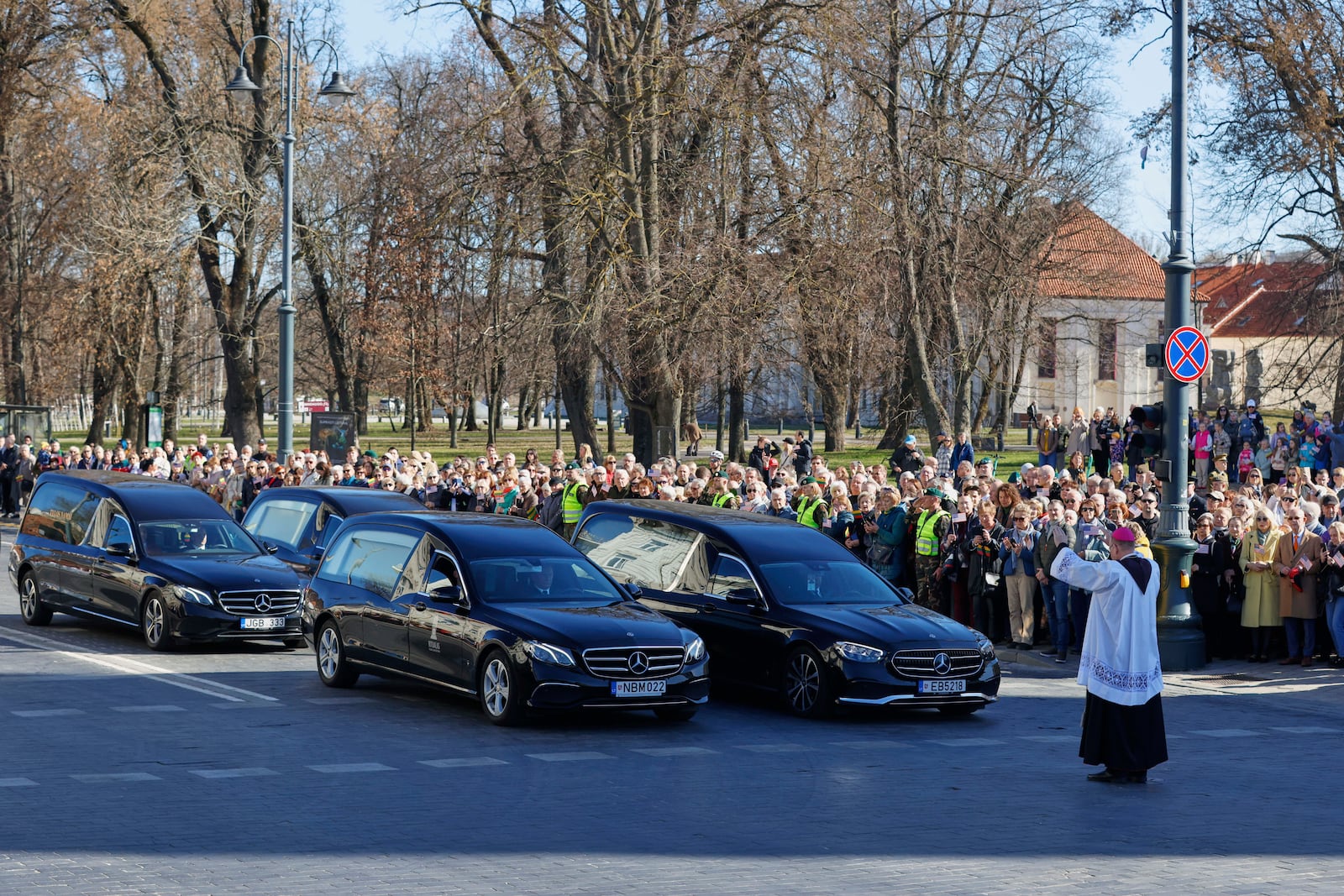 A Catholic priest makes a service in front of a motorcade of catafalques during a solemn farewell ceremony at Cathedral Square in Vilnius, Lithuania, Thursday, April 3, 2025 for the US soldiers who died during training exercise. (AP Photo/Mindaugas Kulbis)