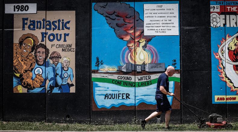 Dayton Firefighter Mike Brown cuts grass in front of a a mural depicting the history of Dayton firefighting on Buckeye St. Friday June 24, 2022.  On Saturday at 1:00p.m. there will be a dedication of the mural and the public is invited. JIM NOELKER/STAFF