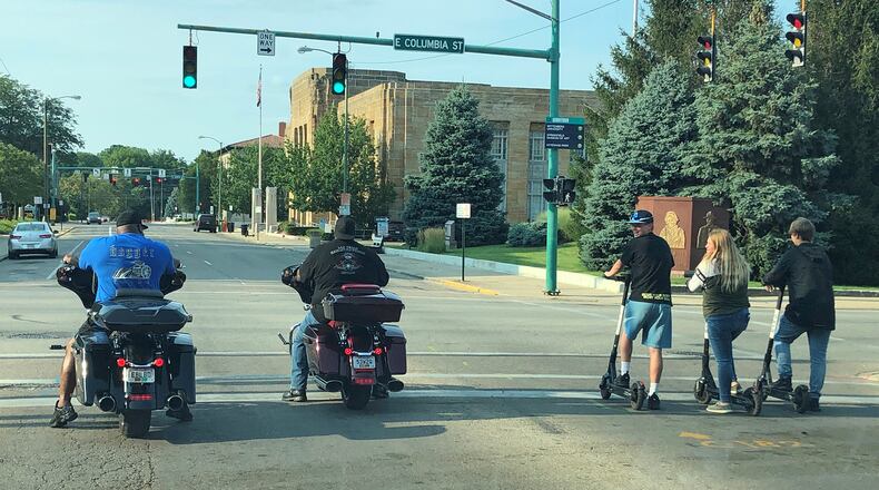 Scooter riders pull up alongside two motorcyclists at the intersection of East Columbia and North Limestone Streets after Bird Ride electric scooters began operating in downtown Springfield in July. CONTRIBUTED/STEPHEN SHARP.
