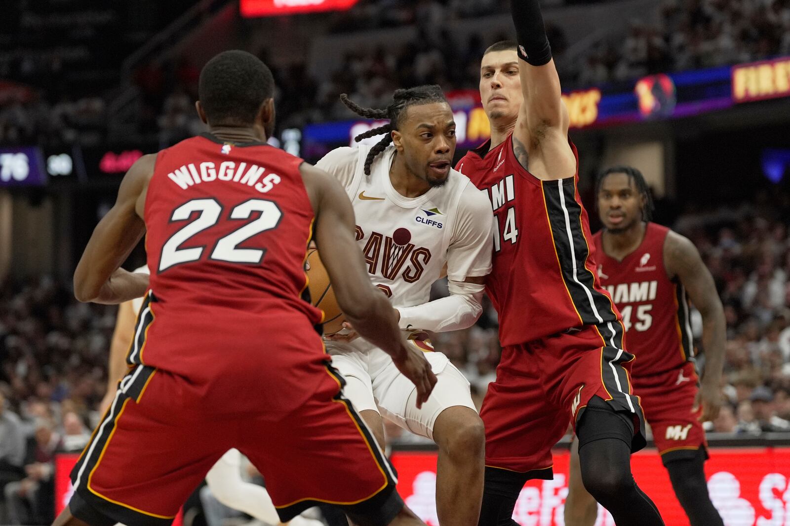 Cleveland Cavaliers guard Darius Garland, center, drives between Miami Heat forward Andrew Wiggins (22) and guard Tyler Herro (14) in the second half in Game 1 of an NBA first-round playoff series, Sunday, April 20, 2025, in Cleveland. (AP Photo/Sue Ogrocki)