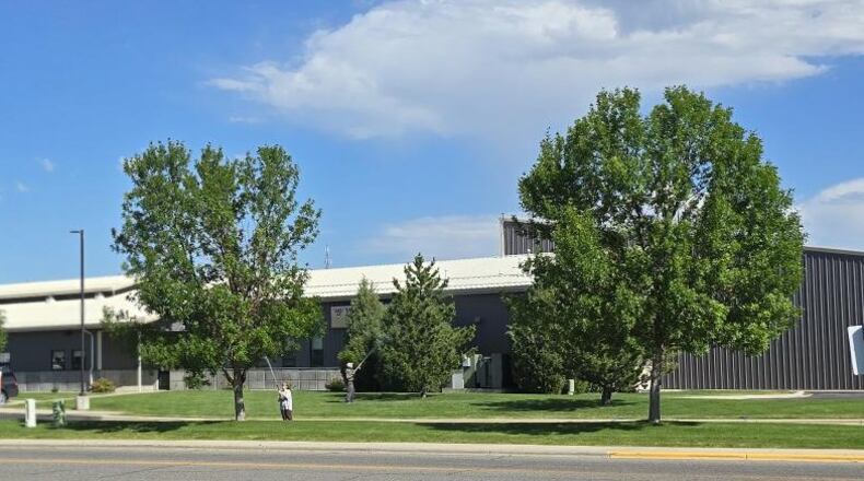 The two people near the trees are spraying a pesticide mix on all of the trees on the property.