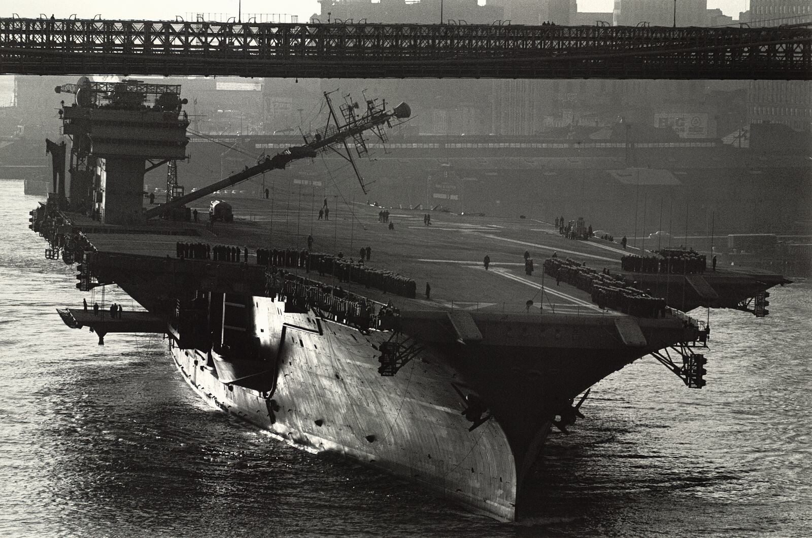 This 1961 image provided by Cornell University/Herbert F. Johnson Museum of Art shows the U.S.S. Constellation aircraft carrier passing under the Brooklyn Bridge in New York. The ships had to be designed to be able to lower their masts to pass under the bridge to avoid striking it. (Cornell University/Herbert F. Johnson Museum of Art via AP)