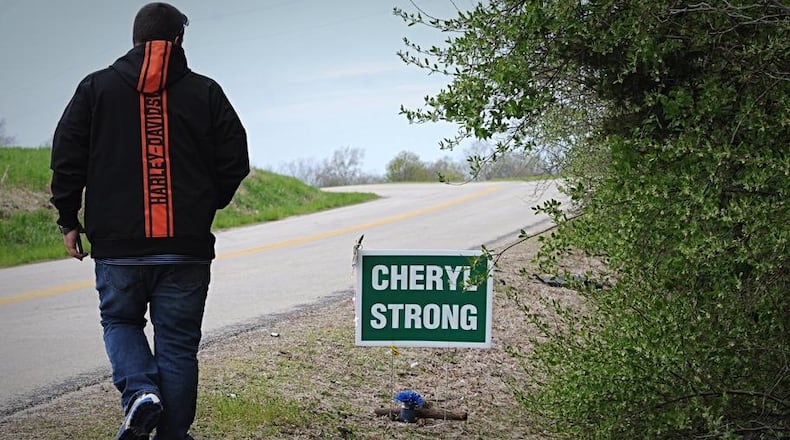 A friend of Cheryl Coker’s is shown next to a sign that was placed near where her remains were found over the weekend in Greene County. MARSHALL GORBY / STAFF