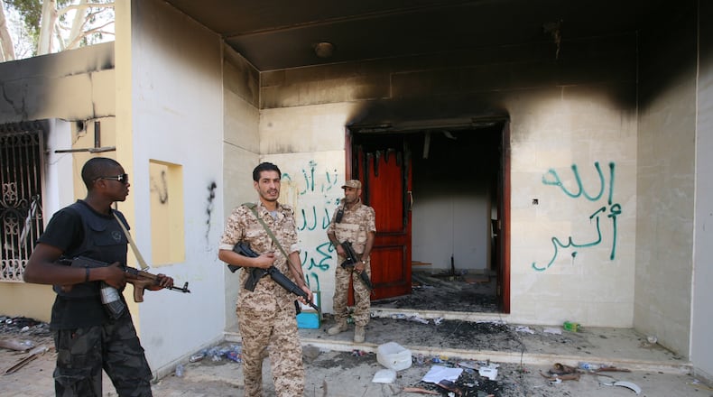 FILE - Libyan military guards check one of the U.S. Consulate's burnt-out buildings, Sept. 14, 2012, during a visit by Libyan President Mohammed el-Megarif, not pictured, to the U.S. Consulate to express sympathy for the death of American ambassador Chris Stevens and his colleagues after the deadly attack on the Consulate on Sept. 11, in Benghazi, Libya. (AP Photo/Mohammad Hannon, File)