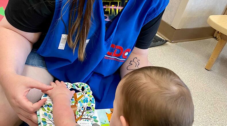 Sam Conner, a child care technician, reads a book to Georgia Rupert at the New Horizon Child Development Center on Wright-Patterson Air Force Base. Child Development Centers strive to make sure every military member has access to quality, affordable child care. U.S. AIR FORCE PHOTO/SENIOR AIRMAN EMILY RUPERT