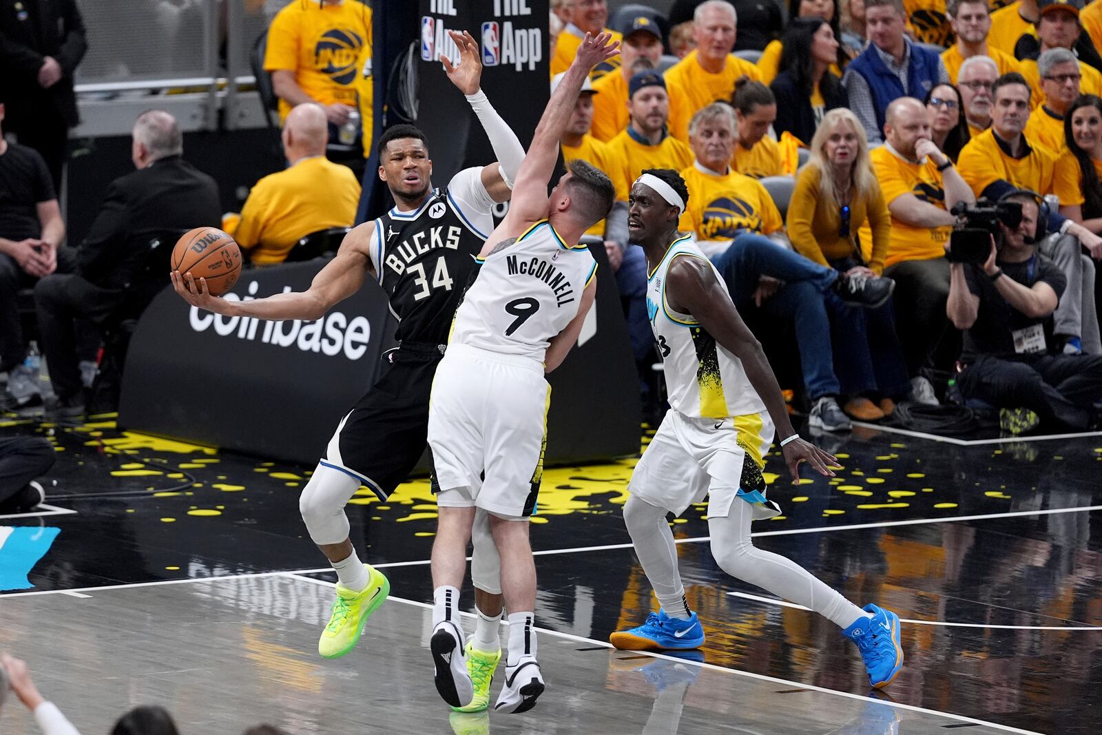 Milwaukee Bucks' Giannis Antetokounmpo (34) looks to pass as Indiana Pacers' T.J. McConnell (9) and Pascal Siakam defend during the second half of a first-round NBA basketball playoff game, Saturday, April 19, 2025, in Indianapolis. (AP Photo/Michael Conroy)