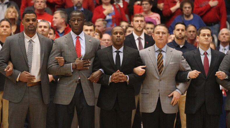 Dayton coaches (left to right) Ricardo Greer, Anthony Grant, Anthony Solomon, Donnie Jones, Darren Hertz and Andy Farrell stand during the national anthem before a game against Purdue Fort Wayne on Friday, Nov. 16, 2018, at UD Arena. David Jablonski/Staff