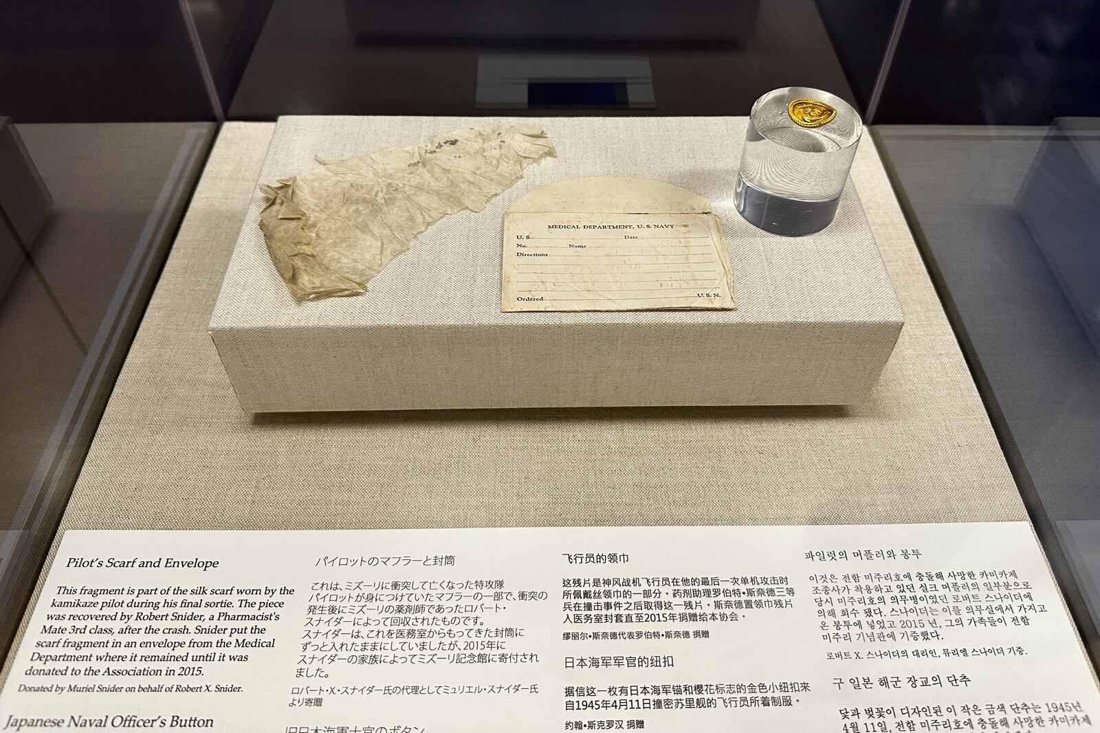 A fragment of a silk scarf and a button worn by the kamikaze pilot of a Japanese zero plane that rammed into the USS Missouri during the Battle of Okinawa is on display at the Battleship Missouri Memorial in Pearl Harbor on April 3, 2025. (AP Photo/Audrey McAvoy)