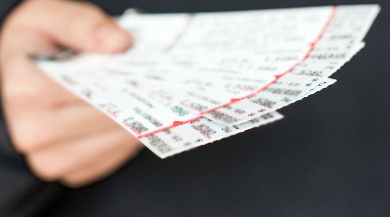 Tickets to a show / event in a hand with a black background.