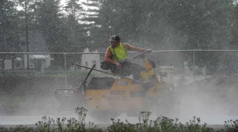 The summer rain and heat is big challenge workers who make their living outdoors. The steam rises off the street in Kettering during paving, Monday, June 7, 2021. MARSHALL GORBY\STAFF