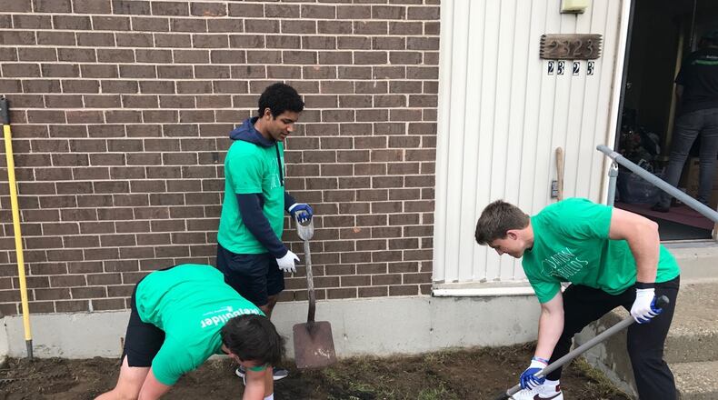 Dayton Flyers teammates (left to right) quarterback Ryan Van Schelven, wide receiver Kyle Hazell and quarterback Cole Dow put in a flower bed in front of Hazel Higgins’ home on Weaver Street Saturday as part of the Rebuild Together Dayton effort. (Tom Archdeacon photo)