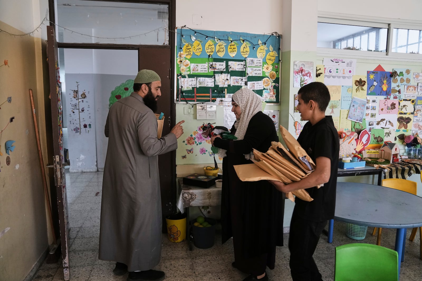 A student and a teacher carry study material at UNRWA School run by the U.N. agency for Palestinian refugees in the Shuafat Refugee Camp in east Jerusalem, Thursday, May 8, 2025. After Israeli forces ordered the closure of six of its schools in east Jerusalem Thursday. (AP Photo/Mahmoud Illean)