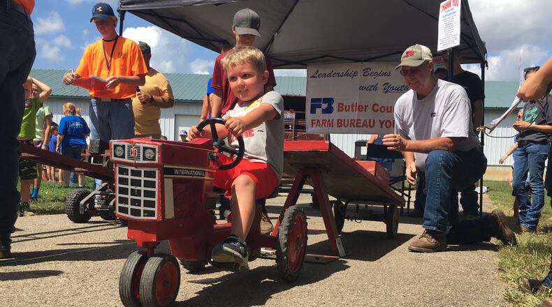 Four-year-old Bryce Clawson competes in the Kiddy Tractor pull, with the help of Farm Bureau member Dave Lierer on Friday, July 27, at the Butler County Fair. JACKIE OSBORNE/STAFF