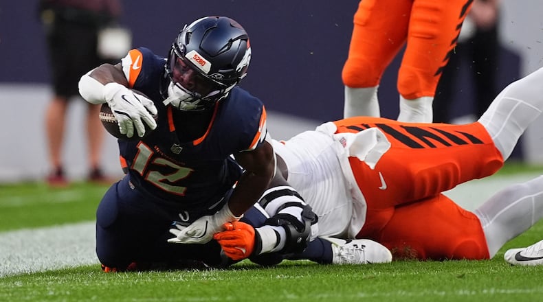 Cincinnati Bengals defensive tackle Tedarrell Slaton (98) tackles Denver Broncos running back RJ Harvey (12) during the first half of an NFL football game Monday, Sept. 29, 2025, in Denver. (AP Photo/David Zalubowski)