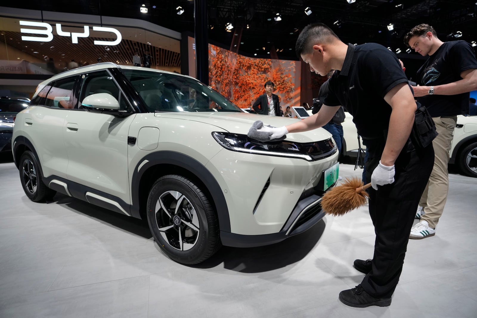 A worker polishes the surface of a BYD car during the Shanghai auto show on Wednesday, April 23, 2025. (AP Photo/Ng Han Guan)