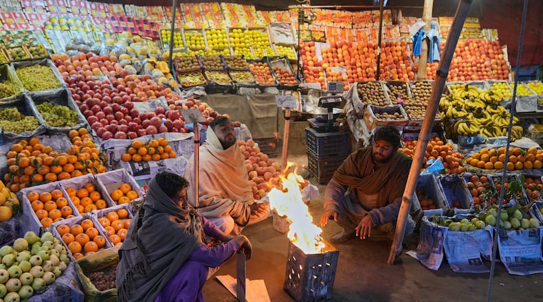 Vendors warm themselves around a fire on a cold morning in Lahore, Pakistan, Tuesday, Dec. 9, 2025. (AP Photo/K.M. Chaudary)