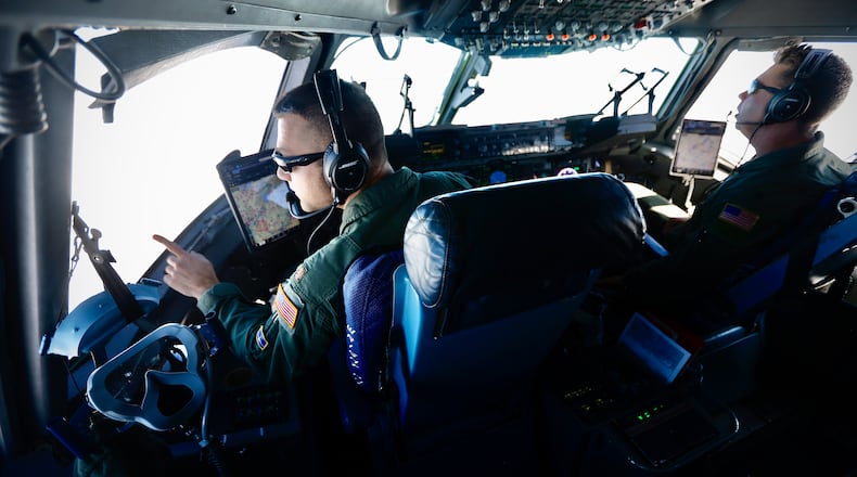 Maj. Trevor Tomlin, left, gestures inside the cockpit of a C-17 Globemaster III flying 27,000 feet in altitude Wednesday, Oct. 16, 2024. To Tomlin's right is Lt. Col. Keith Buddelmeyer. Both men are pilots with the 445th Airlift Wing based at Wright-Patterson Air Force Base. The wing flew 1,240 sorties in fiscal year 2024. MARSHALL GORBY \STAFF
