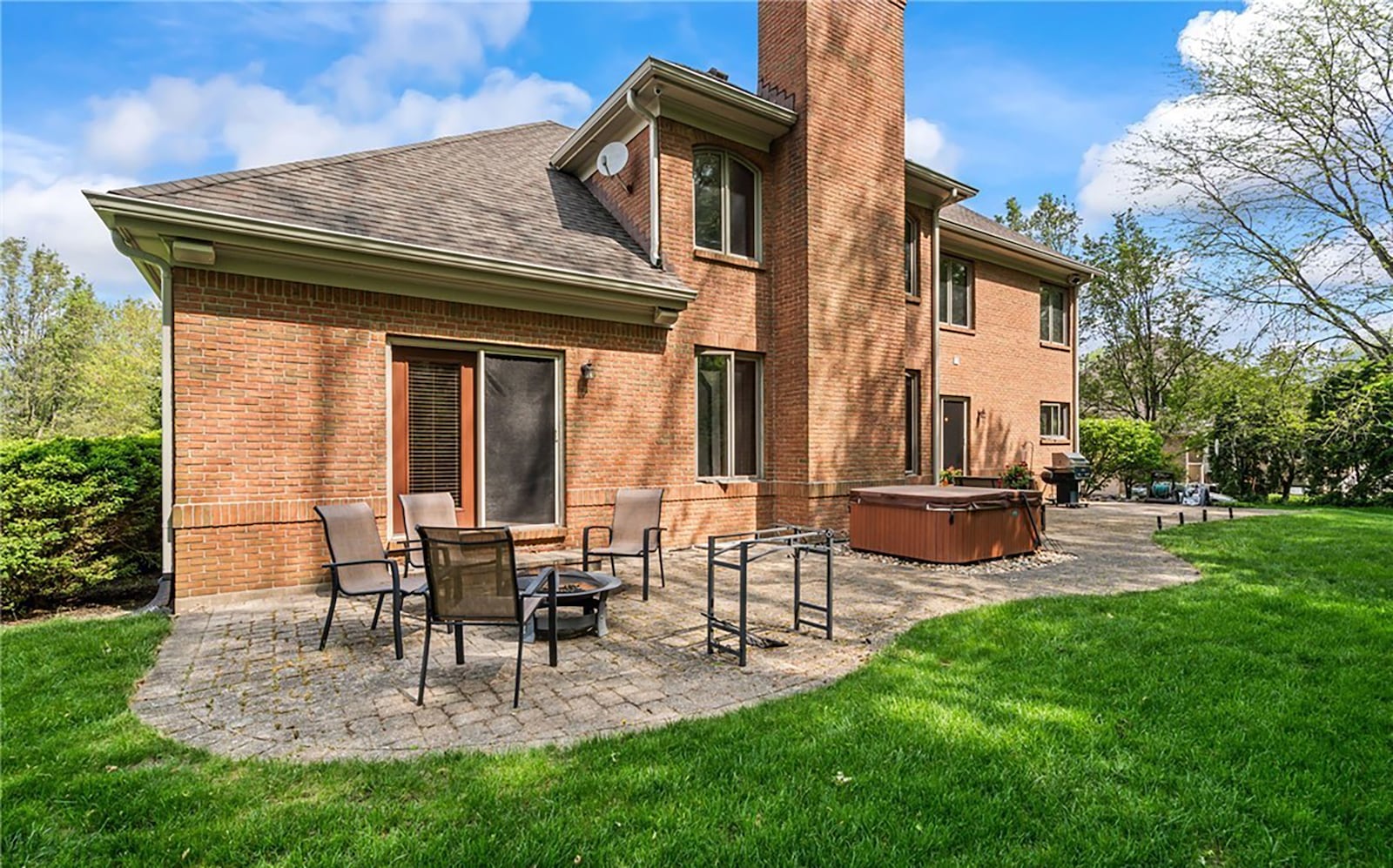 The rear of the home has an extended size paver patio and a hot tub and the back of the lot is lined with trees.