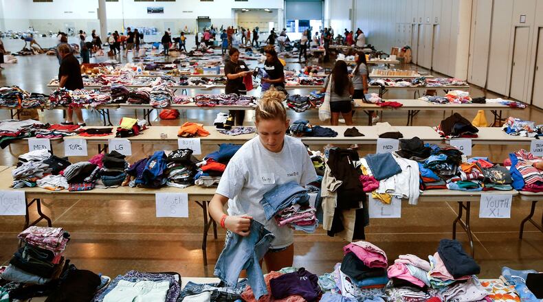 Volunteer Paige Atkinson sorts donated clothing at NRG Center, which opened its doors to evacuees in the wake of Tropical Storm Harvey Wednesday, Aug. 30, 2017 in Houston. Officials say nearly all Houston-area waterways inundated by Harvey’s record rainfall have crested, but that water levels continue to rise in two flood-control reservoirs. (Michael Ciaglo /Houston Chronicle via AP)